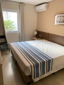 库里提巴Hotel Sol By MRHotelaria的一间卧室配有一张带蓝白条纹毯子的床