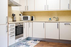 索尔德乌Apartamento Luxury en Bordes d'Envalira, Andorra的白色的厨房配有白色的橱柜和微波炉