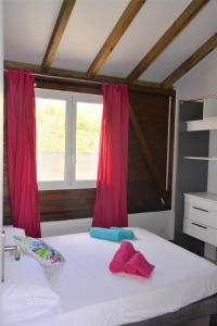 勒马兰Maison Ste Anne/Marin Piscine personnelle vue sur mer的卧室配有白色的床和红色窗帘
