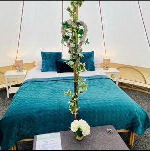 牛津牛津河畔豪华帐篷的一间设有蓝色床单和鲜花的床的客房