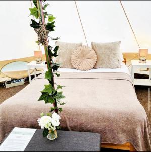 牛津牛津河畔豪华帐篷的一间卧室配有一张床和一张鲜花桌子