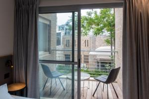 耶路撒冷Urbanic Hotel的客房设有带2把椅子和1张桌子的阳台。