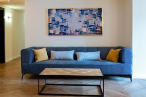 耶路撒冷Urbanic Hotel的客厅里一张蓝色的沙发,上面有绘画作品