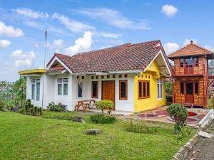 西昆都尔SPOT ON 91107 Villa Galaxy Resort的一座黄色和白色的小房子,有院子