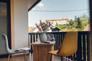 ŽužemberkGostišče Koren的阳台配有两把椅子和一张带花瓶的桌子