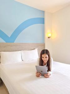 宿务Hop Inn Hotel Cebu City的一位妇女躺在床上,使用笔记本电脑
