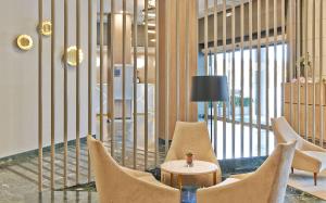 萨拉戈萨NH萨拉戈萨城市酒店的大堂设有椅子和一张带台灯的桌子