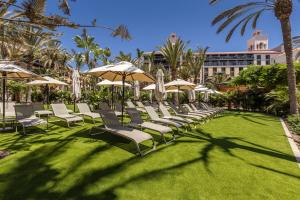 梅罗那瑞斯Lopesan Costa Meloneras Resort & Spa的草坪上的一组躺椅和遮阳伞