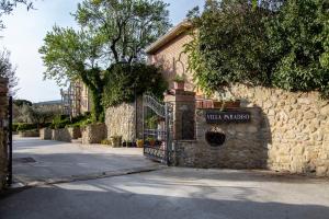 特拉西梅诺湖畔帕西尼亚诺Hotel Villa Paradiso的街道上一座石头建筑,设有大门