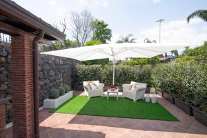 阿奇雷亚莱Villa Arianna的一个带遮阳伞、椅子和草地的庭院