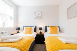 霍兹登Velvet 2-bedroom apartment, Brewery Road, Hoddesdon的黄色和白色的客房内的两张床