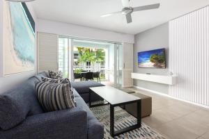 道格拉斯港Beach Club Port Douglas Luxury Apartments的客厅配有蓝色的沙发和桌子