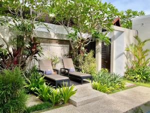 迈考海滩Sunset Ocean Front Villa , Mai Khao Phuket的庭院设有两把椅子,种有树木和植物