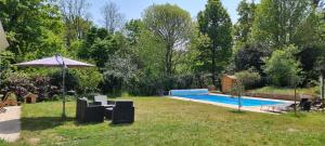Villiers-sous-GrezJolie maison en pleine nature的后院设有游泳池和遮阳伞