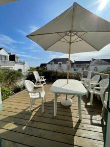 洛克马里亚Maison de vacances de 56 m2 dans résidence avec piscine chauffée proche plages的甲板上配有桌椅和遮阳伞