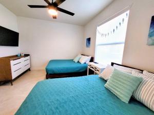 珊瑚角Blue Door Retreat - Luxury Pool Home - sleeps 8的一间卧室配有两张床和吊扇