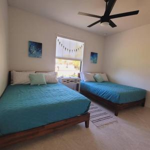 珊瑚角Blue Door Retreat - Luxury Pool Home - sleeps 8的一间卧室配有两张床和吊扇