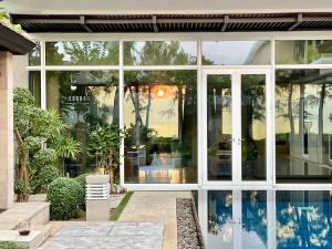 迈考海滩Sunset Ocean Front Villa , Mai Khao Phuket的一座玻璃房子,在院子里设有一个游泳池