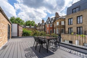 伦敦Be London - The Bloomsbury Residences的阳台的天井配有桌椅