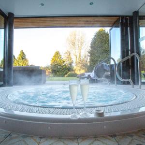赛伦塞斯特Stratton House Hotel & Spa的热水浴池,配有2个香槟杯