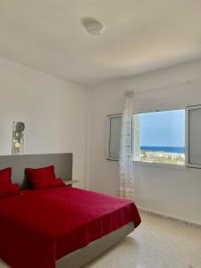 哈马马特Soltane Résidence的白色的卧室设有红色的床和窗户