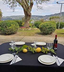 蓬特德乌梅Hostal San Cristobal - Pontedeume的一张带盘子和玻璃杯的黑桌和一瓶葡萄酒