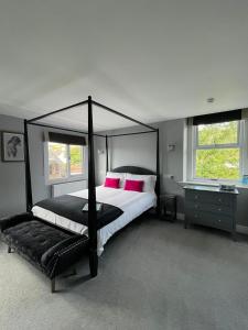 切达Gordons的一间卧室配有黑色天蓬床和粉红色枕头