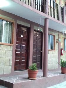 贝纳尔Hotel Villas Kerendarhú的一座建筑,有两扇棕色门和两棵盆栽植物