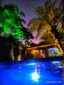哥伦布Bangalô das Lagartixas ,casa stúdio com piscina aquecida privativa a 20 minutos do Centro de Curitiba的棕榈树游泳池和灯塔建筑