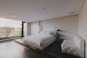 光州ACC设计酒店的白色卧室配有一张大床和椅子