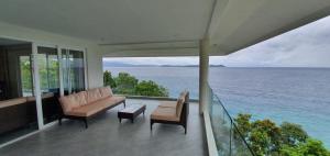 PinamihaganLuxury 3 Bed, 2 Bath Apartment with Stunning Panoramic Sea View, Private Beach的阳台配有沙发和椅子,享有海景。