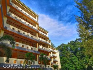 卢穆特Apartment Teluk Batik的一座大建筑,有树木背景