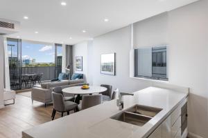 悉尼Meriton Suites Coward Street, Mascot的厨房以及带桌椅的起居室。