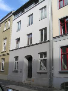 施特拉尔松德Ferienwohnungen Langenstraße - Altstadt的享有白色建筑的外部景色,设有红色窗户