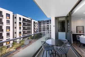 悉尼Meriton Suites Coward Street, Mascot的阳台配有桌椅和建筑