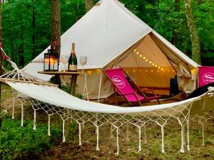 SwaderkiCaravana Juliana - Glamping的帐篷配有吊床和带葡萄酒瓶的桌子
