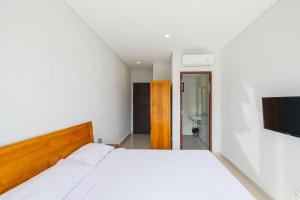 塞米亚克Dharma Guest House Seminyak RedPartner的一间带白色床的卧室和一间浴室