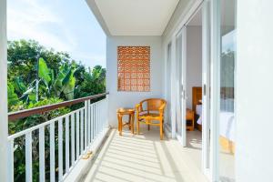 塞米亚克Dharma Guest House Seminyak RedPartner的客房设有带椅子和桌子的阳台。