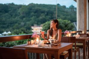 卡伦海滩Mandarava Resort and Spa, Karon Beach - SHA Extra Plus的坐在餐厅桌子上的女人
