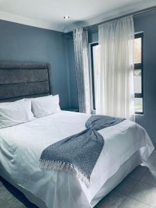 路易特里哈特President Guest Lodge的卧室配有一张白色的床,床上有毯子