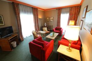 布罗马纳普林坦尼亚宫殿酒店的客厅配有红色椅子和电视