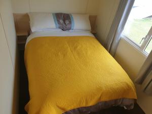 斯凯格内斯4 BERTH CARAVAN SILVER BEACH INGOLDMELLS number 90的一个小房间,设有一张黄色的床,窗户