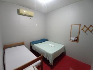马瑙斯Discovery hostel的小房间设有两张床和镜子