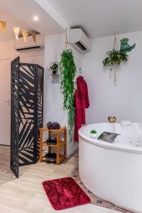 PézarchesSuite L'echappee - Maison romantique - SPA & Sauna Privatif- Pole Dance - Lit rond avec miroir au plafond的浴室设有白色浴缸和红色地毯。