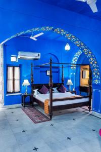 斋浦尔Diggi Palace A Luxury Heritage Hotel的一间拥有蓝色墙壁的卧室和一张位于客房内的床