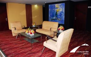 托卢卡Hotel Concorde Toluca的一间设有桌椅和绘画的等候室