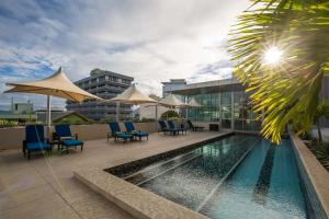 莫尔兹比港Grand Papua Hotel, a member of Radisson Individuals的一座大楼内的游泳池,配有椅子和遮阳伞