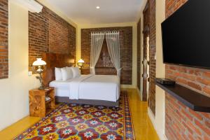 斯勒曼Bale Devata Resort的配有一张床和一台平面电视的酒店客房