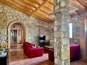 梅基嫩萨Casa Rural Mas de les Àligues的客厅设有红色椅子和石墙