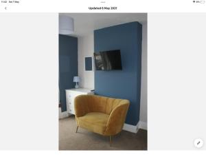 克里基厄斯Beachside holiday house的蓝色墙壁的房间里一张黄色椅子